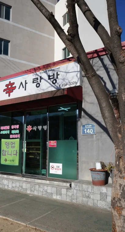 가게 건물 — 간판 «辛사랑방», 붉은 차양, 유리문, 도로명 번호판 140, 가로수