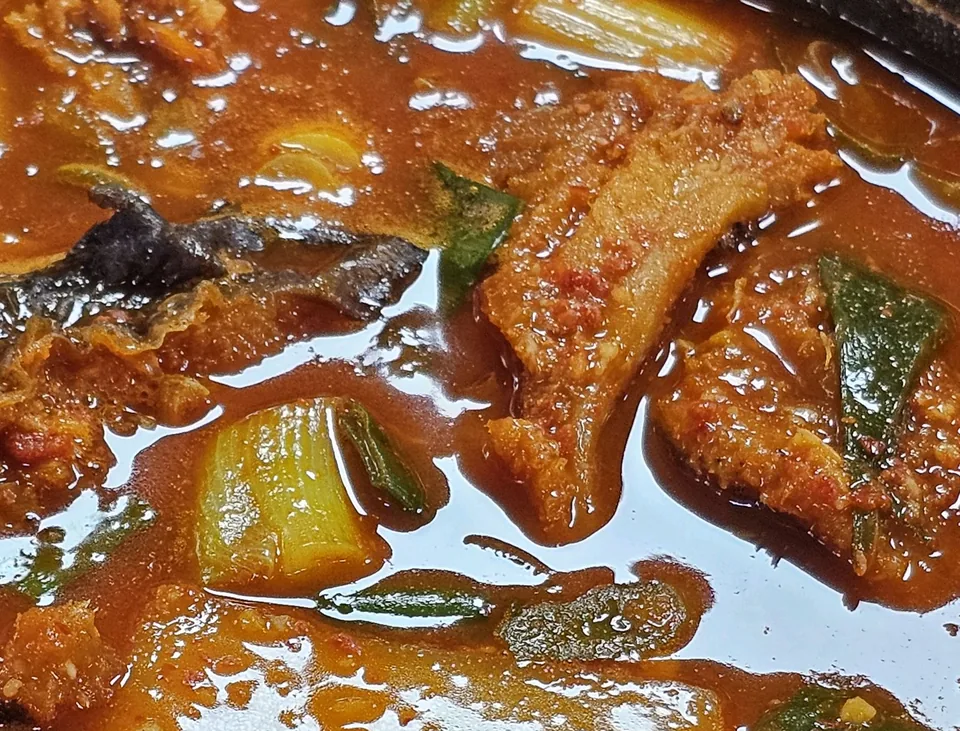 끓고 있는 북어물찜을 가까이 — 붉은 국물 속 북어 조각과 대파