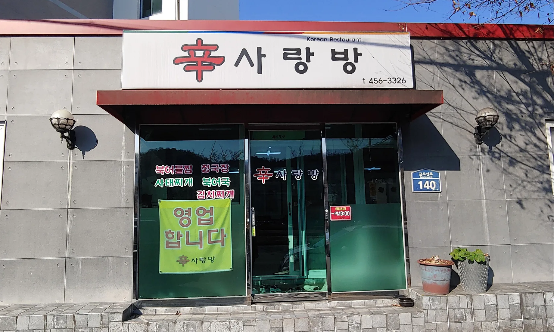 가게 앞 — 간판 «辛사랑방 Korean Restaurant», 유리창의 메뉴 글씨, 도로명 번호판 «금오산로 140»